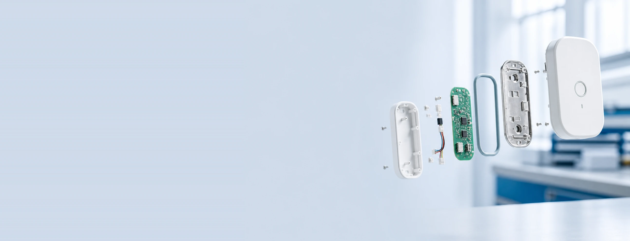 Exploded view of a compact electronic device: outer housing, populated PCB, wiring harness, seal and die-cast bracket
